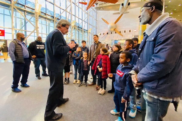 Children and adults mingle in a large lobby decorated with model aircraft.