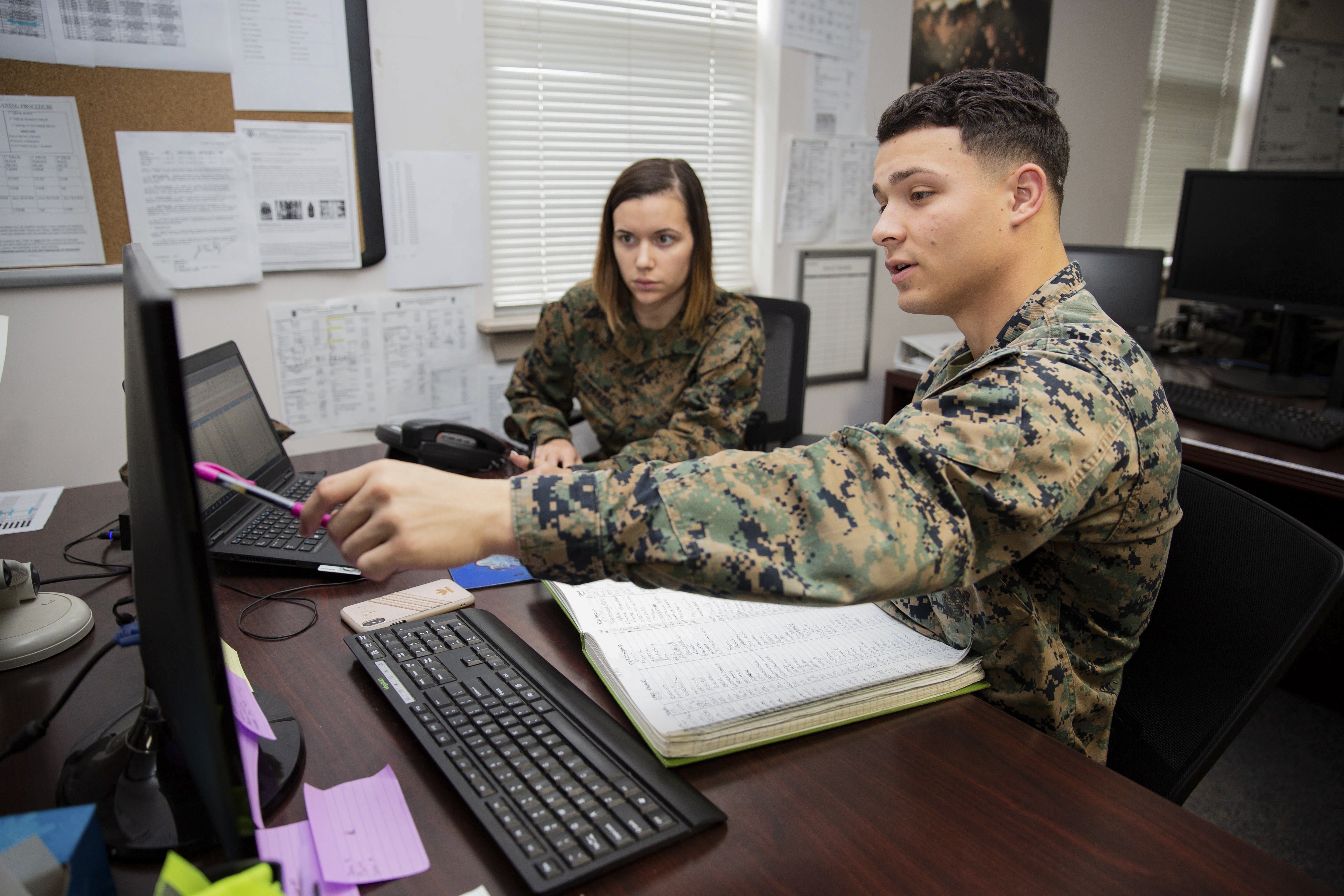U.S. Marine Corps Cpl. Elliot Blake, right, provides administrative support to Cpl. Natasha Herrera, both administration specialists with Headquarters and Support Battalion, at the Installation Personnel Administration Center (IPAC) on Marine Corps Base Camp Lejeune, North Carolina, Jan. 16, 2020. The mission of the IPAC is to provide personnel administrative support and services to service members and family members to ensure military personnel records and pay accounts are accurate and properly maintained in order to prepare the individual for worldwide deployment with the operating forces. (U.S. Marine Corps photo by Cpl. Karina Lopezmata)