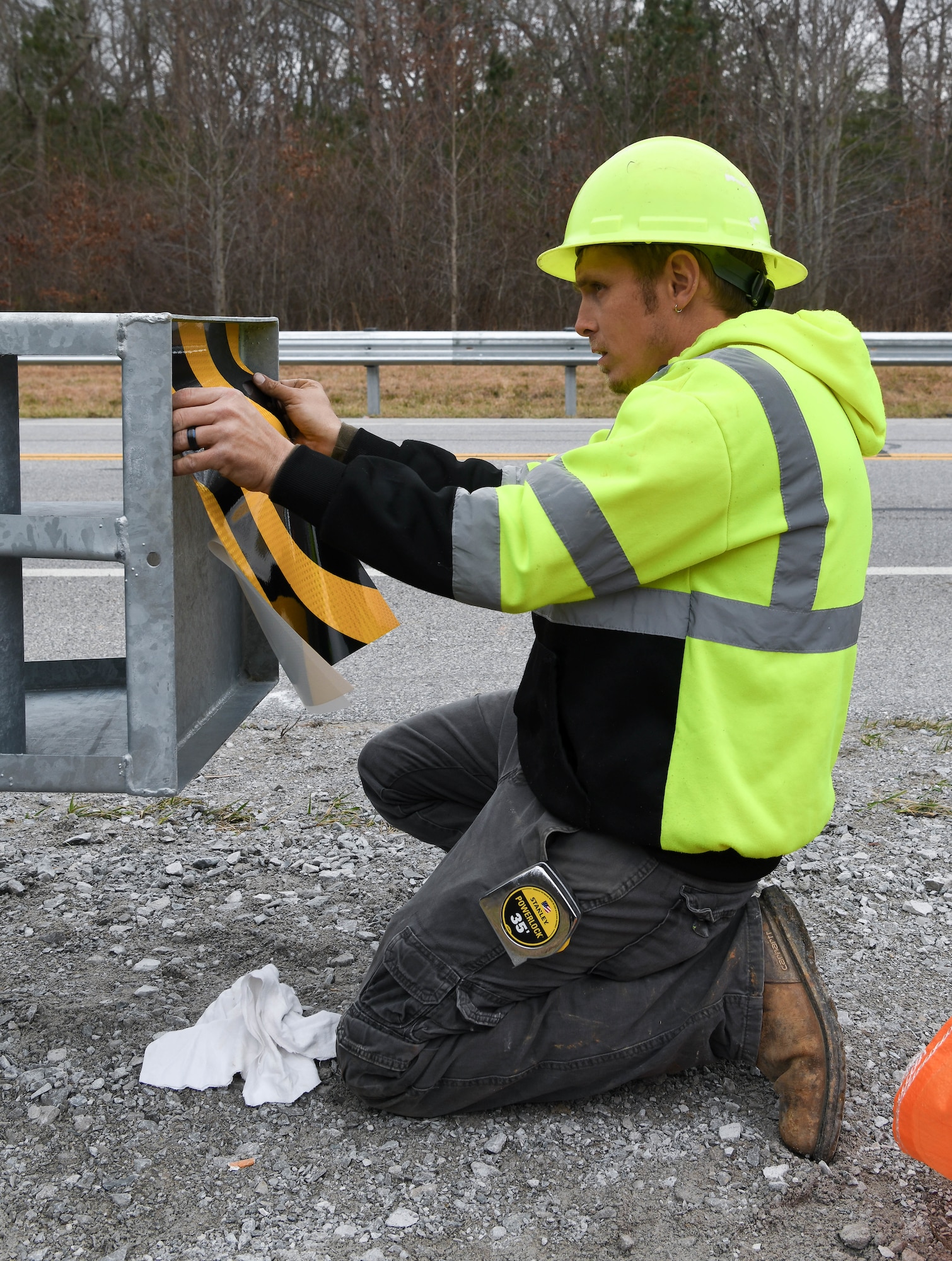 Billy Clemons adds a sticker to the end of a section of guardrail to improve visibility of the hardware as he and a crew install new guardrails along Wattendorf Memorial Highway at Arnold Air Force Base, Tenn., Jan. 27, 2021. Guardrails were added to areas where the shoulder drops off and at bridge ends to increase safety for motorists. (U.S. Air Force photo by Jill Pickett)