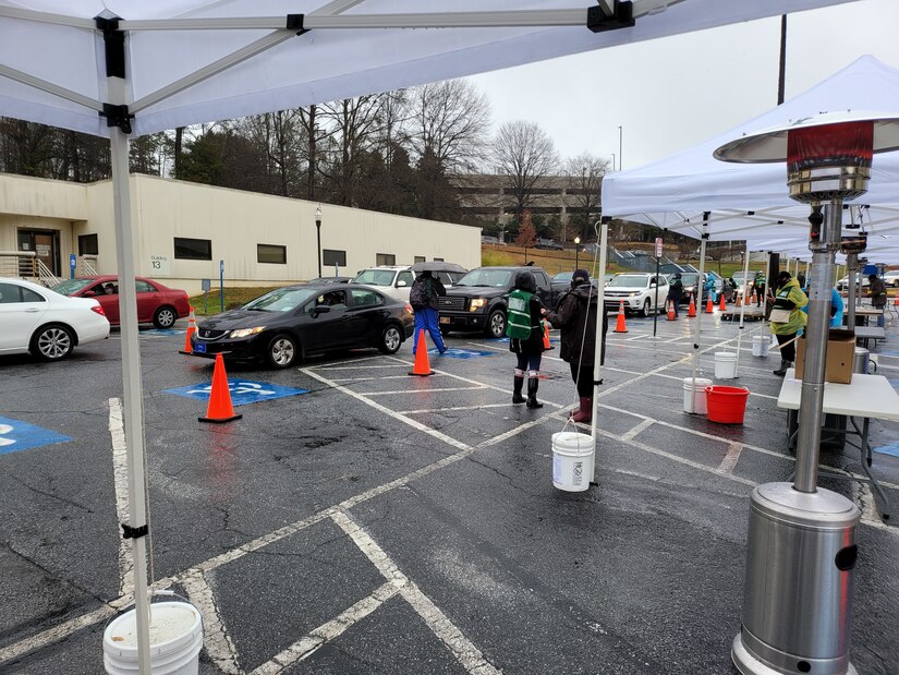 Volunteers from the 3d Medical Command (Deployment Support) and AMEDD Professional Management Command assist with check in at the Atlanta VA Covid-19 vaccine drive-thru, February 13, 2021.