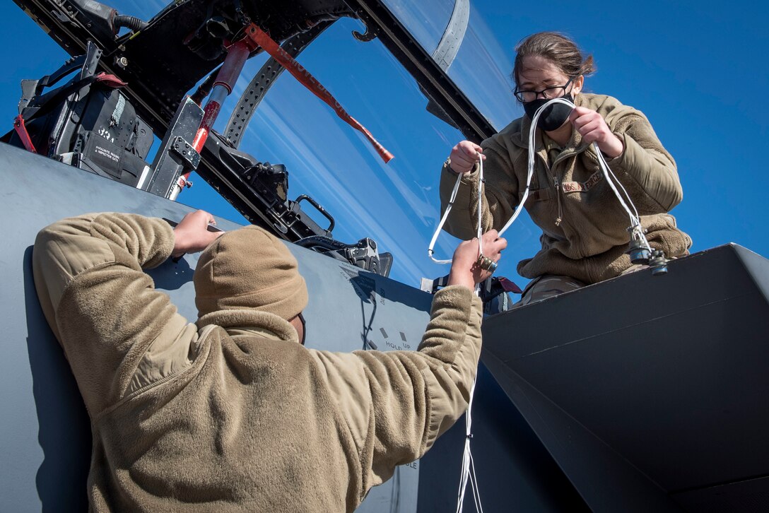 Airman 1st Class Quentin Thompson (left) and Senior Airman Kierra Hamil (right), 4th Component Maintenance Squadron electrical and environmental technicians, pass a testing harness at Seymour Johnson Air Force Base, North Carolina, Feb. 3, 2021.