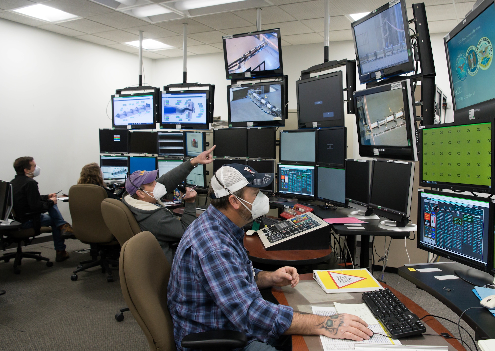 Darren Carroll, a test operations engineer, points to a monitor while directing test operations in the Sea Level 2 Test Cell, Dec. 17, 2020, at Arnold Air Force Base, Tenn. Also pictured, from right, machinist lead Alan Womack and test engineers Jillian Sears and Yancee Burchett. (U.S. Air Force photo by Jill Pickett)