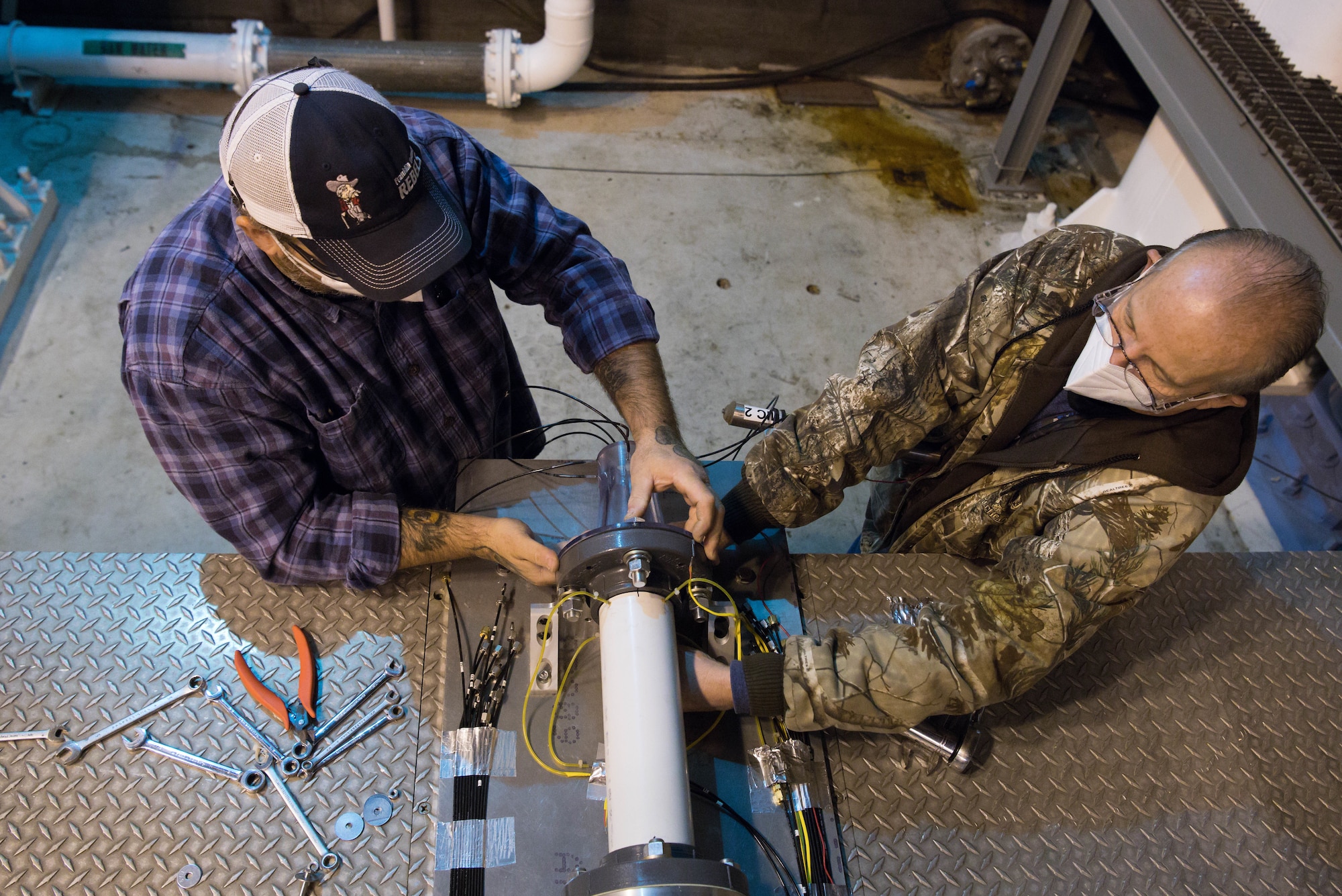 Alan Womack, left, machinist lead, and Jeff Tucker, machinist, install the second of two nozzles onto a test apparatus in the Sea Level 2 Test Cell, Dec. 17, 2020, at Arnold Air Force Base, Tenn. An Arnold Engineering Development Complex test team was researching the acoustic properties of two different nozzles. (U.S. Air Force photo by Jill Pickett)