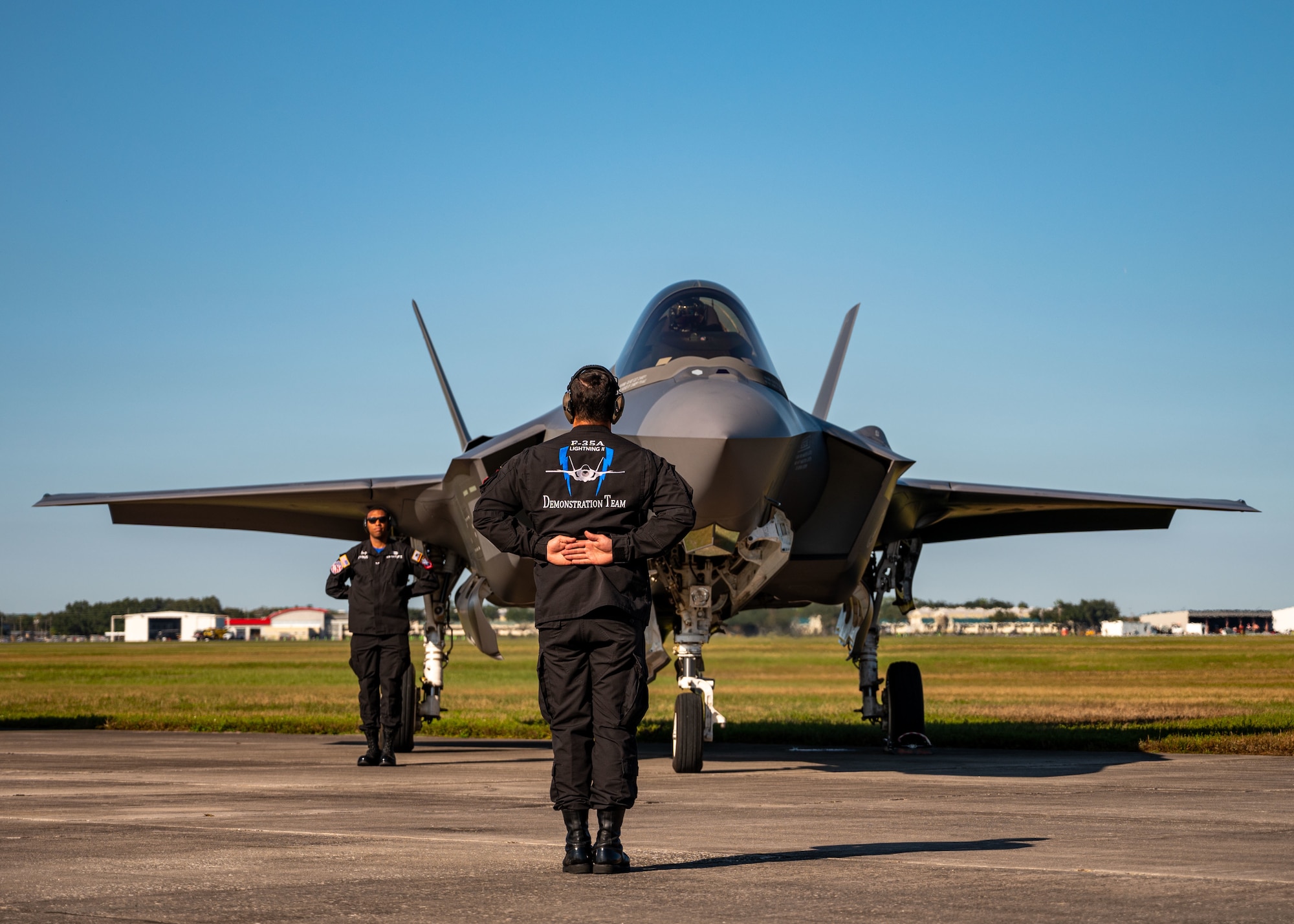 Two Airmen stand next to an F-35 fighter jet.