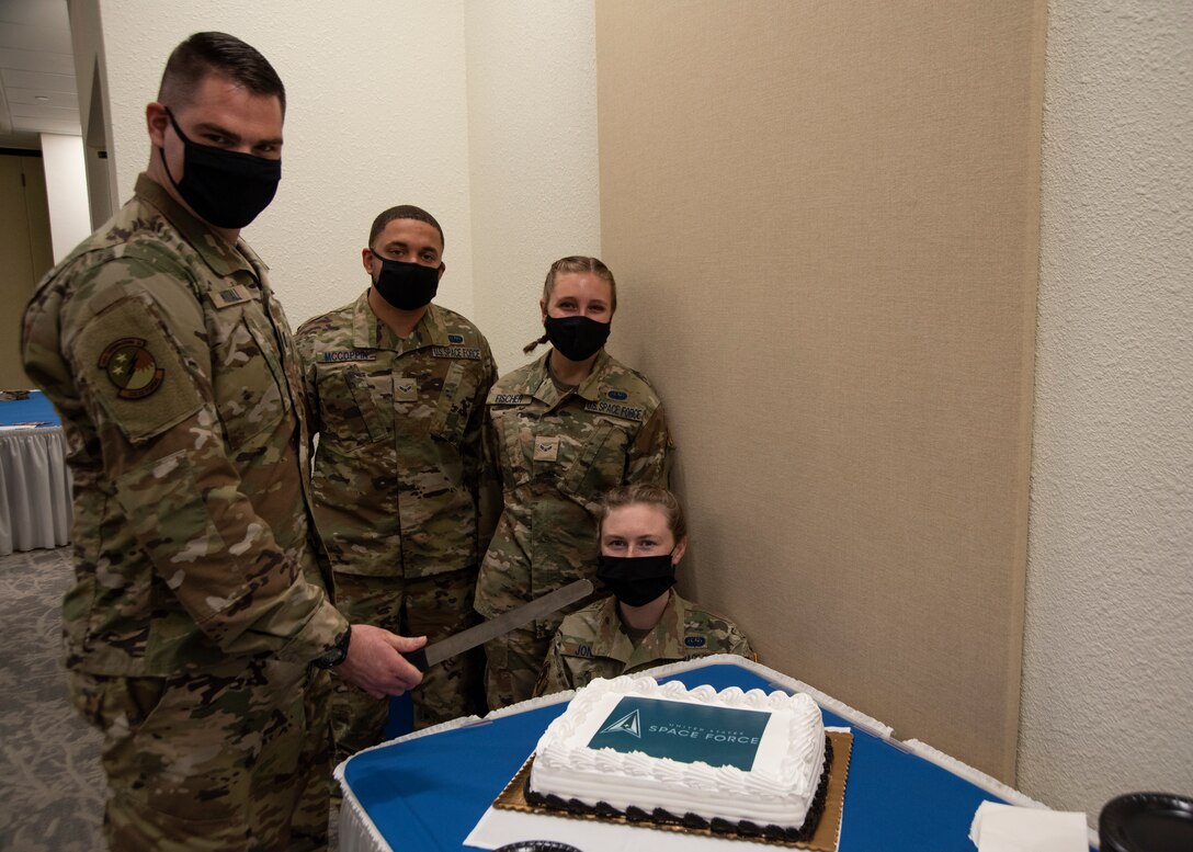 An Specialist officer and three more Specialist are preparing to cut their cake for the celebration of their transfer to the U.S. Space Force.