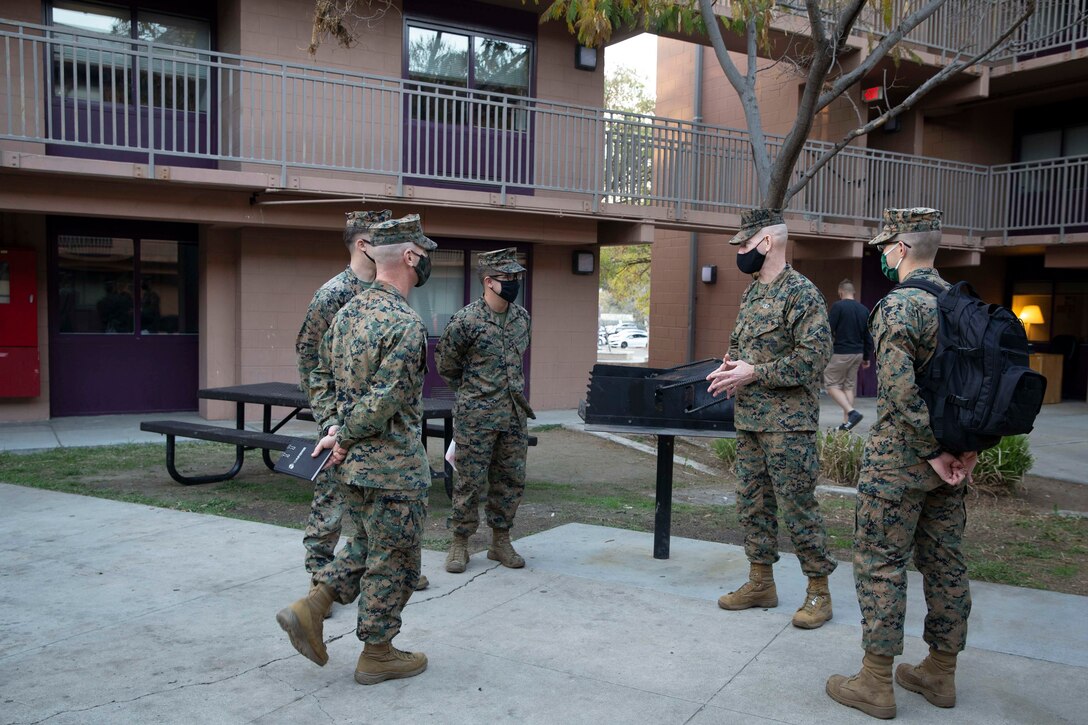 A group of Marines stands talking in front base housing.