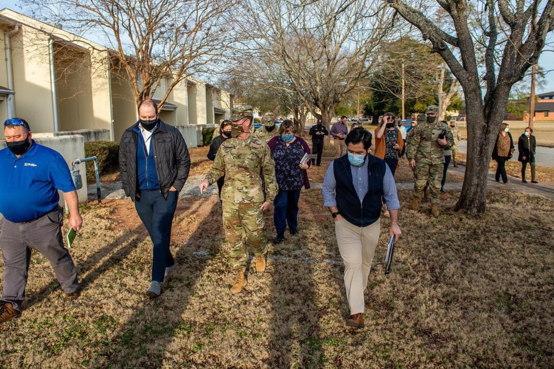 Group of people walk past base housing.