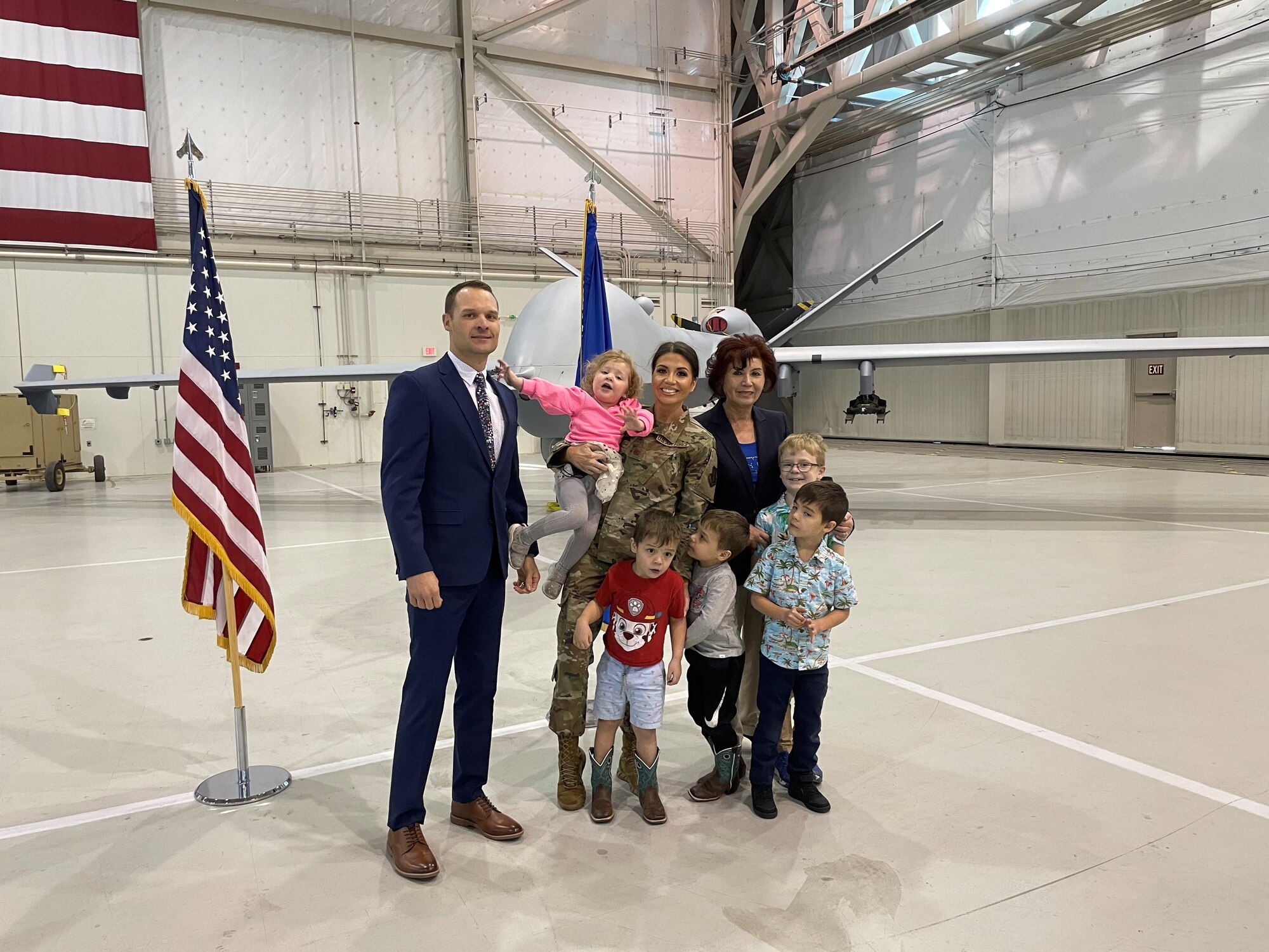 Maj. Jennifer stands with her family in front of an MQ-9 Reaper for a photo.