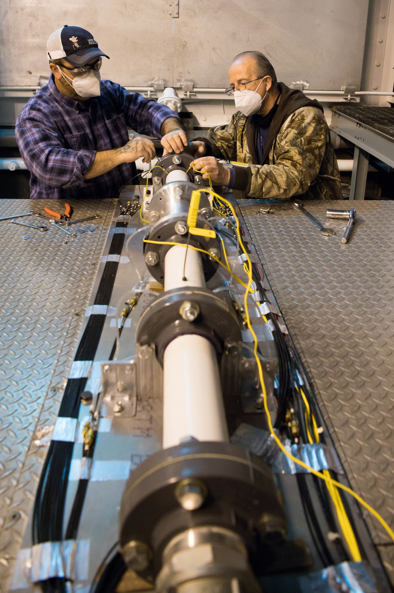 Alan Womack, left, machinist lead, and Jeff Tucker, machinist, install the second of two nozzles onto a test apparatus in the Sea Level 2 Test Cell, Dec. 17, 2020, at Arnold Air Force Base, Tenn. An Arnold Engineering Development Complex test team was researching the acoustic properties of two different nozzles. (U.S. Air Force photo by Jill Pickett)