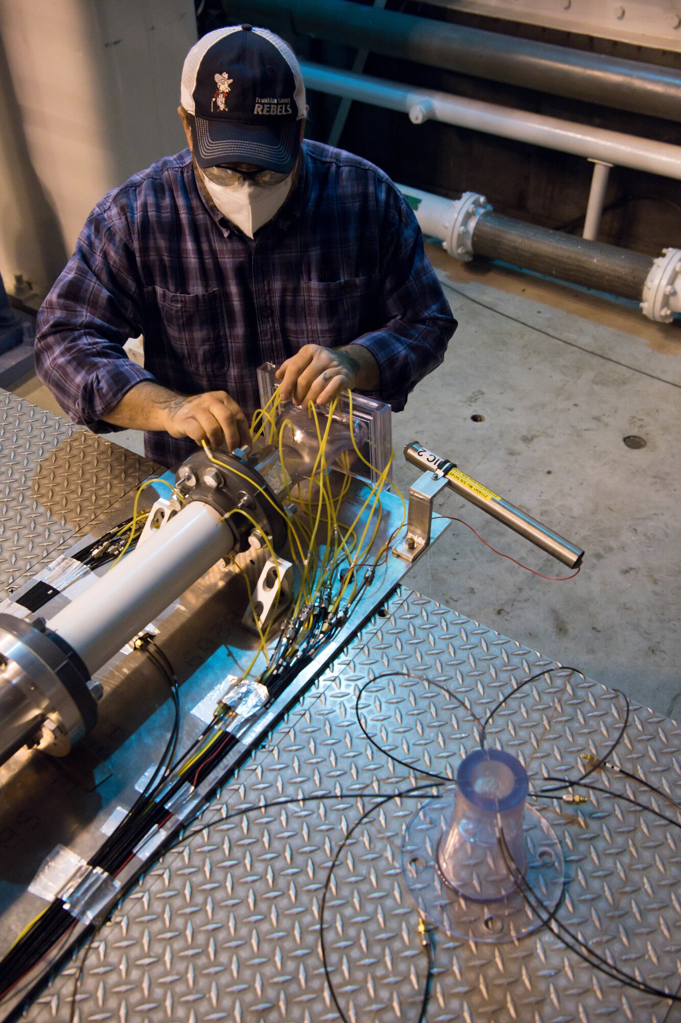 Alan Womack, machinist lead, disconnects instrumentation while preparing to swap out nozzles on a test stand in the Sea Level 2 Test Cell, Dec. 17, 2020, at Arnold Air Force Base, Tenn. The second nozzle that was tested is seen in the foreground. An Arnold Engineering Development Complex test team was investigating the acoustic properties of the nozzles. (U.S. Air Force photo by Jill Pickett)