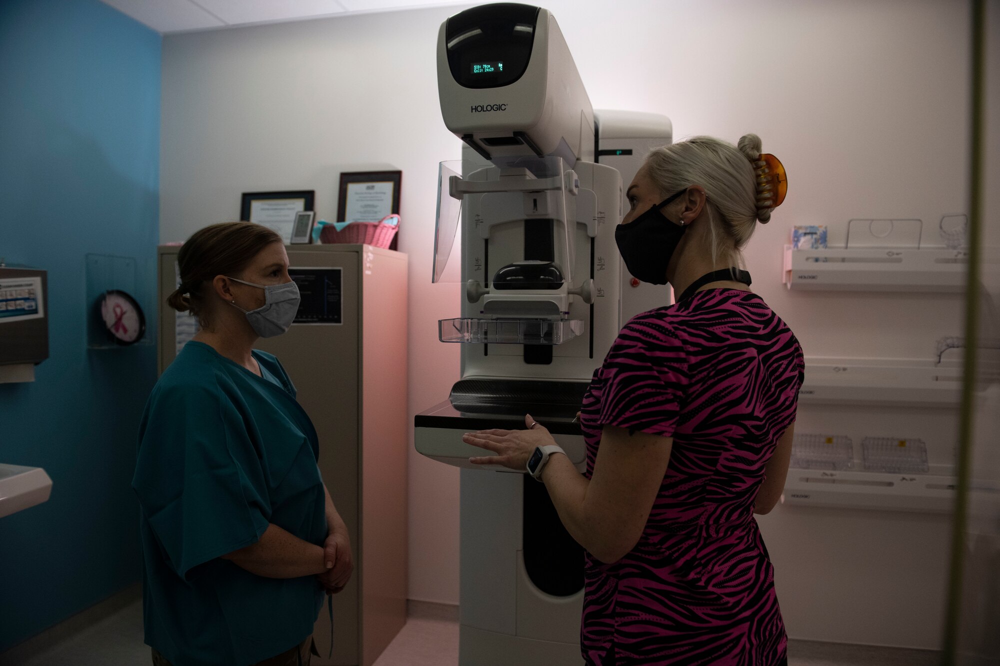 Two women stand in front of a piece of medical equipment.