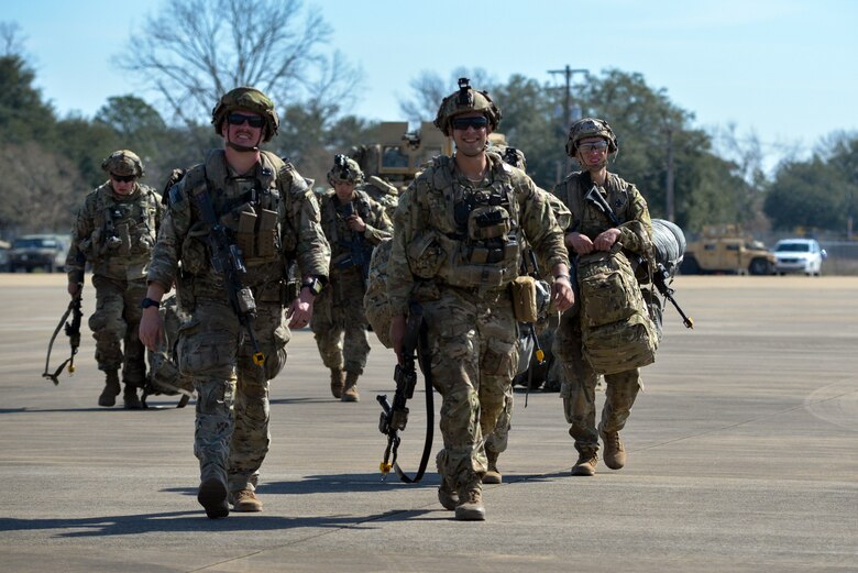 A group of people walk on the flightline