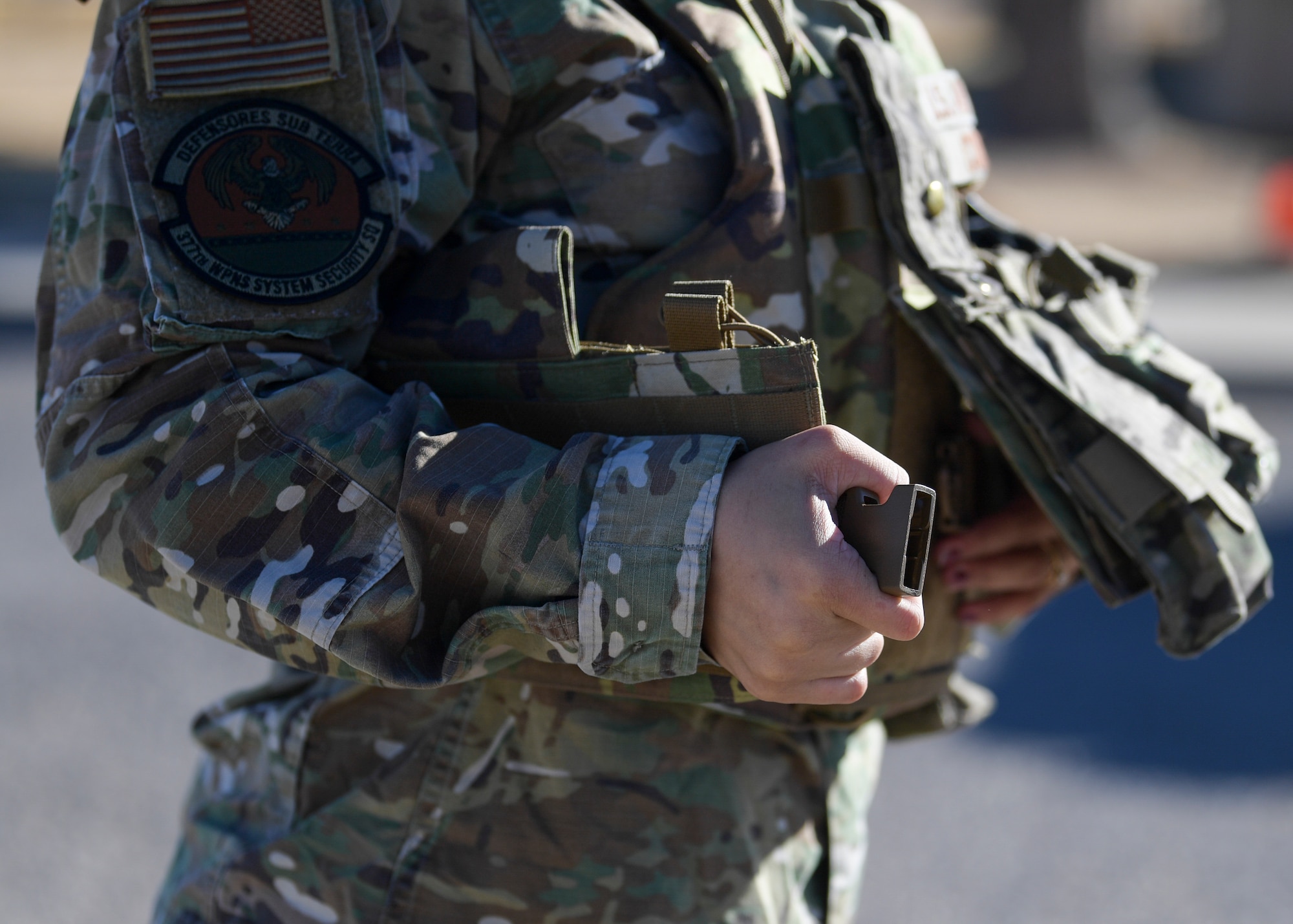 Senior Airman Kiah C. Cook, 377th Security Forces Group defender, donns her body armor at Kirtland Air Force Base, N.M., Feb. 4, 2021. One of the features on the new female body armor is a snap buckle instead of the original velcro, which is used on the standard vest. The adjustable back corset allows the wearer to tighten the fit, making it more secure.