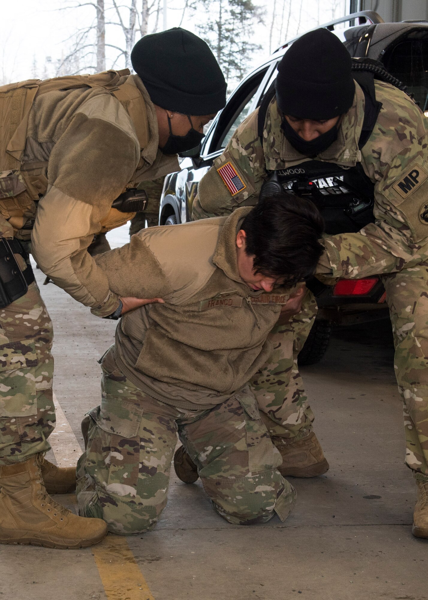 U.S. Army Spc. Derian Callwood, right, a 673 Security Forces Squadron patrolman assigned to the 545th Military Police Company, and U.S. Air Force Tech. Sgt. Jasmine Scott, left, the 673d SFS Kodiak Flight flight sergeant, simulate apprehending U.S. Air Force Senior Airman Lilia Franco, a 673d SFS operations support operations support specialist, as part of a DUI traffic stop demonstration during an immersion with the 673d SFS at Joint Base Elmendorf-Richardson, Alaska, Feb. 2, 2021. The tour familiarized base leadership with the 673d SFS and its role in maintaining the safety of the JBER community and security of the installation and its resources.