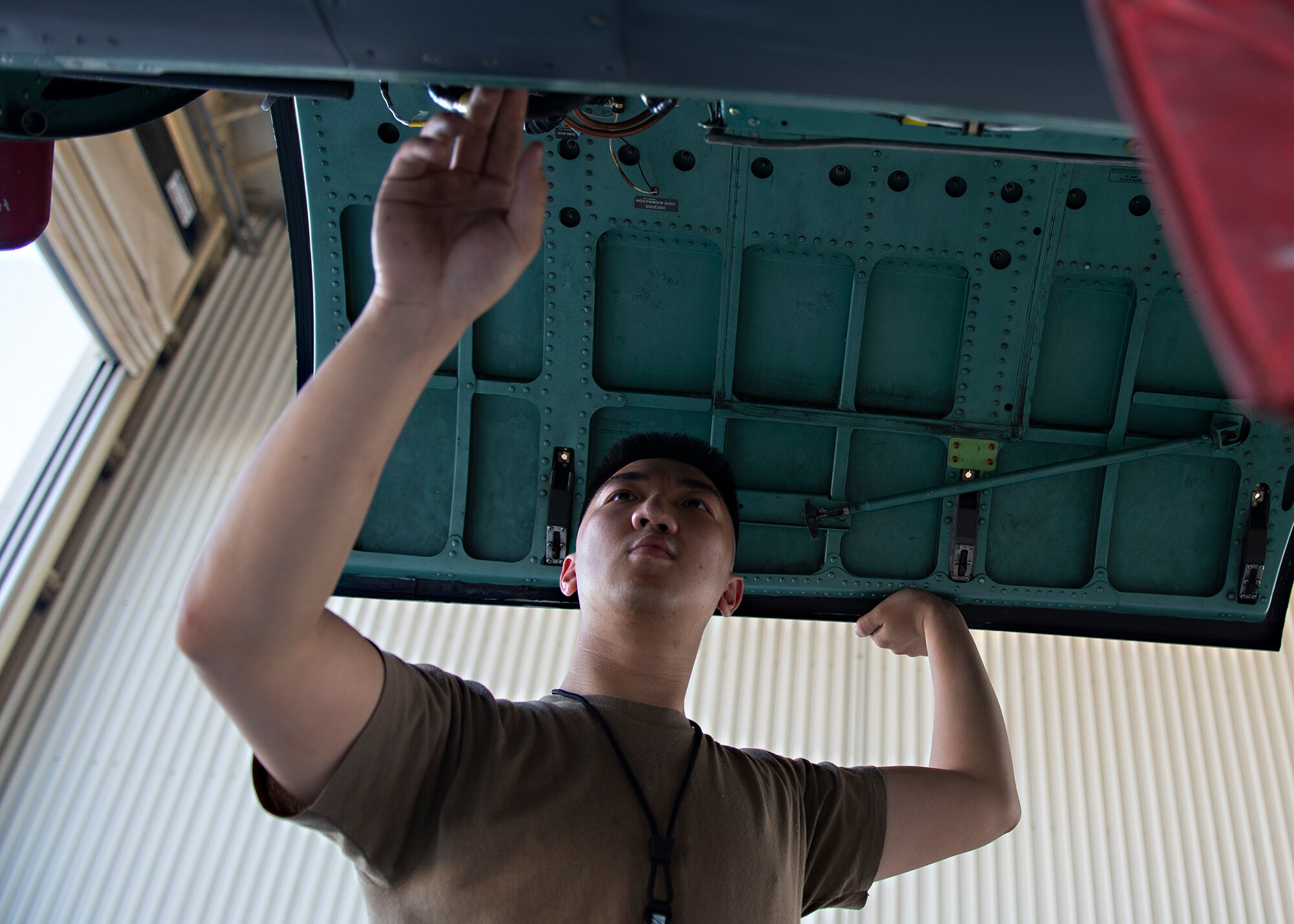 U.S. Air Force Senior Airman James Dang, 380th Expeditionary Aircraft Maintenance Squadron phase inspection journeyman, opens a panel and performs inspections of an F-15E Strike Eagle at Al Dhafra Air Base, United Arab Emirates, Feb. 12, 2021.