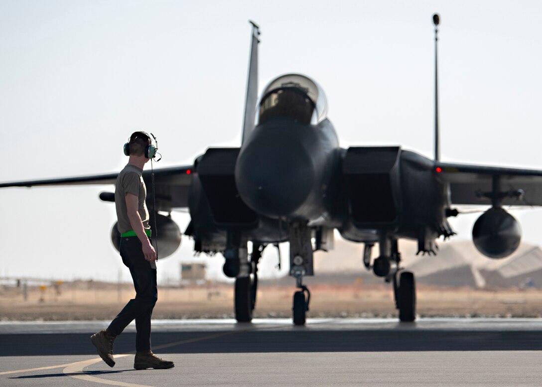 A U.S. Air Force armament systems technician assigned to the 380th Expeditionary Aircraft Maintenance Squadron walks past an F-15E Strike Eagle at Al Dhafra Air Base, United Arab Emirates, Feb. 12, 2021.