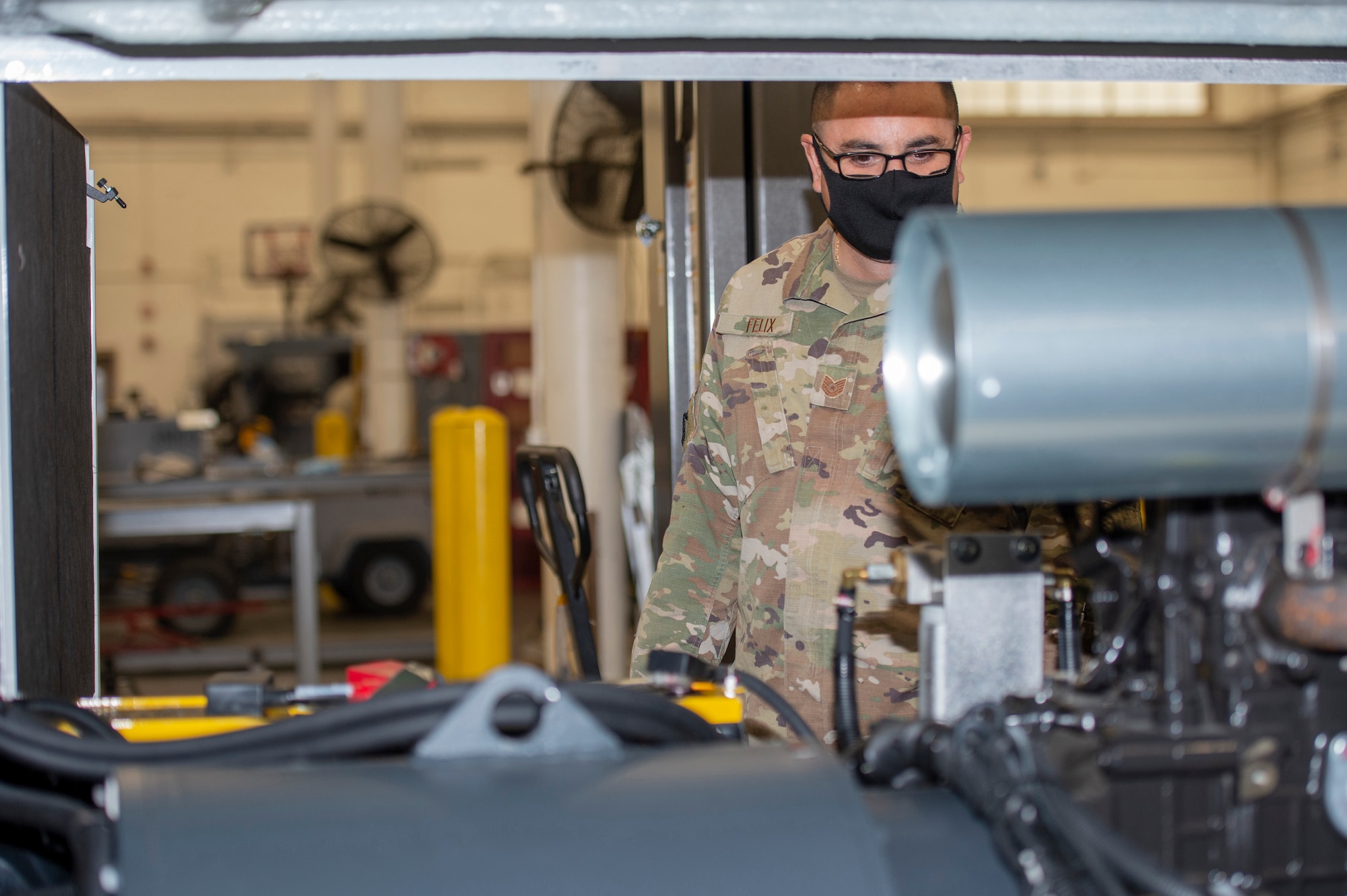 U.S. Air Force Tech. Sgt. Juan Felix, Aerospace Ground Equipment (AGE) production superintendent with the active duty 461st AGE Flight, observes a new ground power unit (GPU) at Robins Air Force Base, Georgia, Jan. 21, 2021. Squadron Innovative Funding used to obtain the new specialized aircraft generators was the first step in Team JSTARS replacing the aging GPUs. (U.S. Air National Guard photo by Master Sgt. Nancy Goldberger)