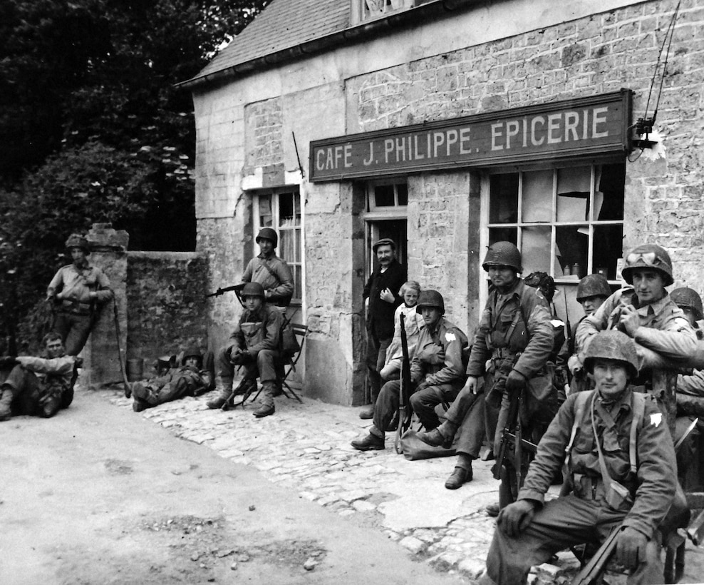 Soldiers relax outside French café, in Sainte-Mère-Eglise, France, June 6, 1944 (National Archives and Records Administration/National Museum of the U.S. Navy)