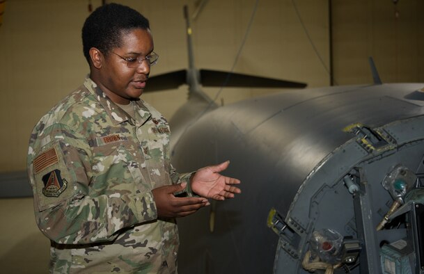 Airman gestures while standing next to a B-1 Lancer