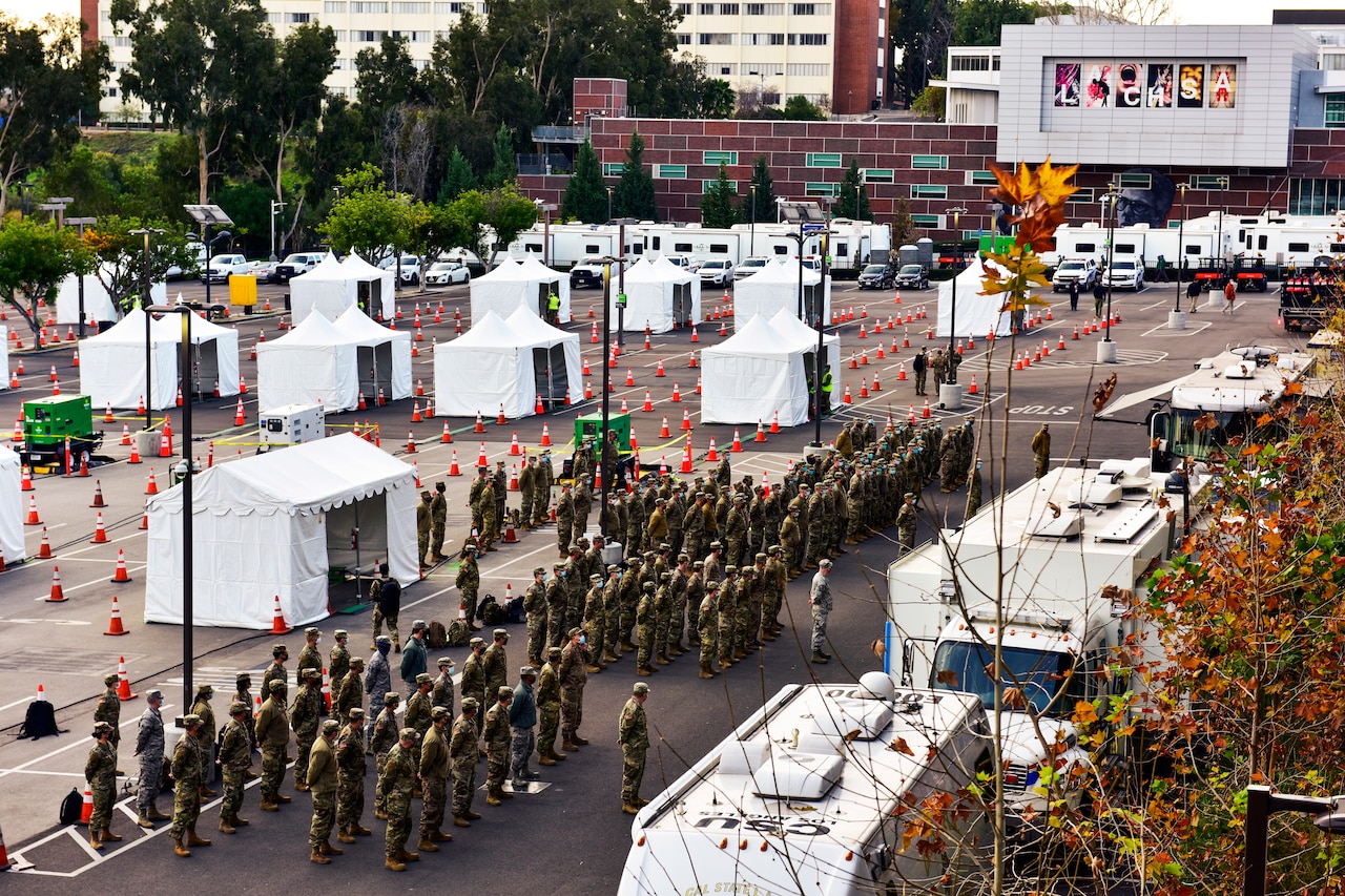 Guardsmen wearing face masks stand at attention during a morning briefing.