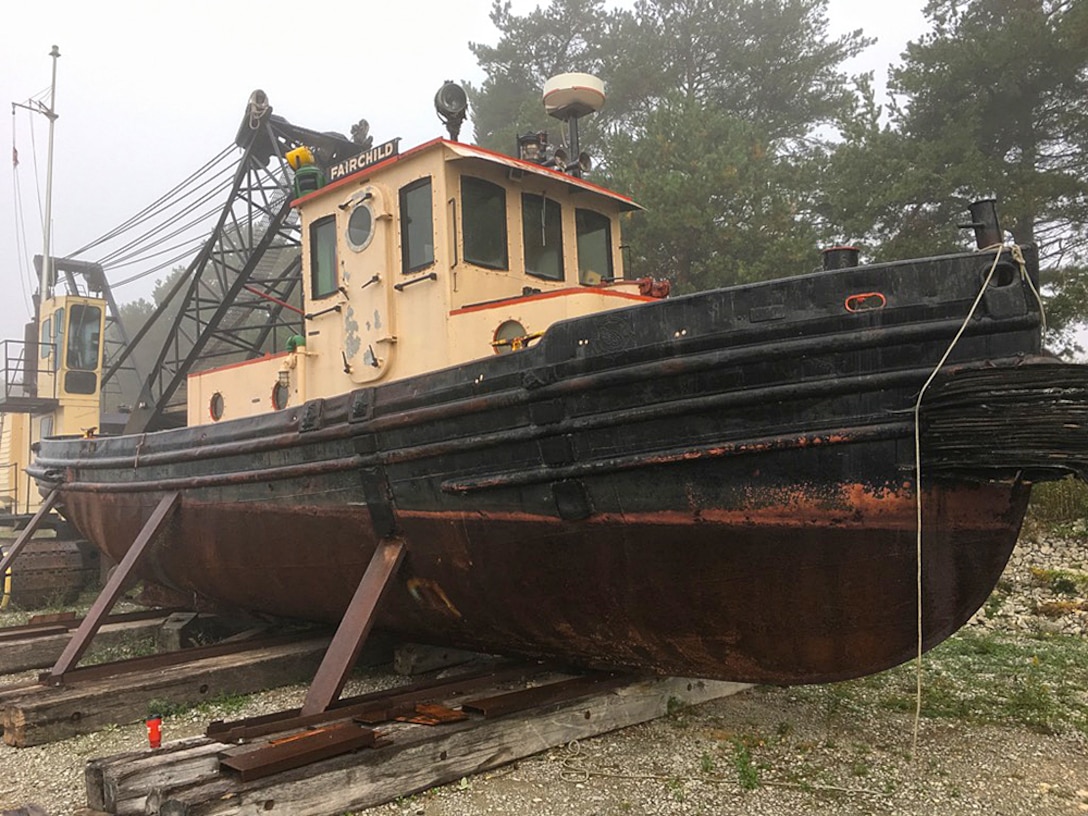 A tugboat in dry storage on a beach.