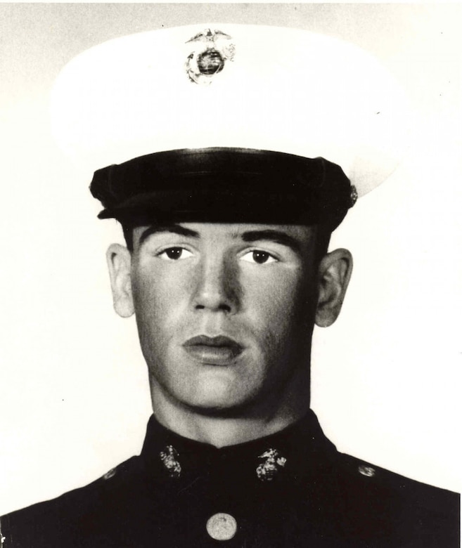 A man in uniform and a dress cap looks straight ahead.