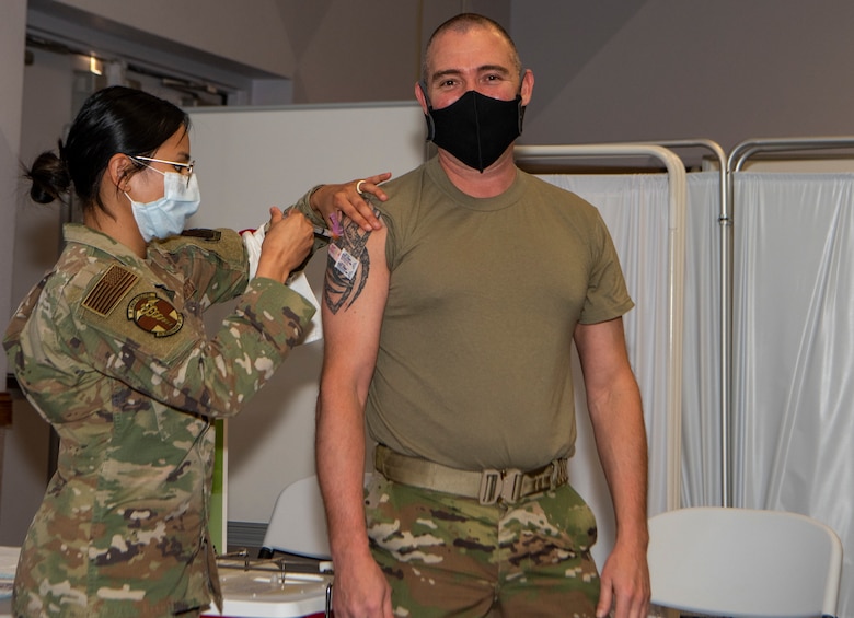 Airman standing receiving a vaccine