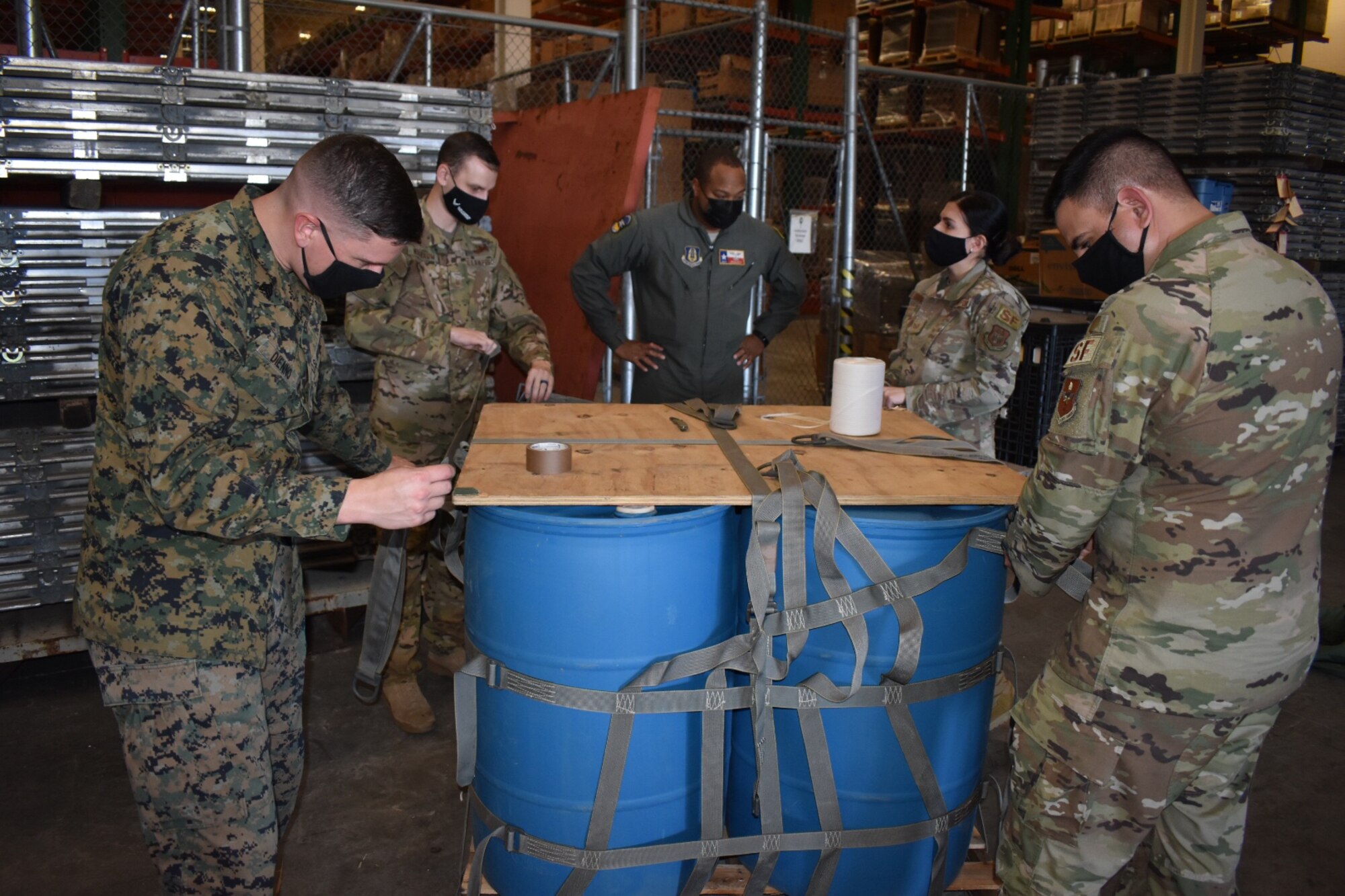 In-service Air Force Reserve recruiters from the 352nd Recruiting Squadron, Master Sgt. Zachary R. Nusbaum, Master Sgt. Bryan Boyd, and Tech. Sgt. Brasil A. Segura (in background from left) team with U.S. Marine Corps Sgt. Robert A. DiEnno, left, 341st Training Squadron, instructor-supervisor for the Military Working Dog Handlers Course, and U.S. Air Force Master Sgt. Matthew D. Dibenedetto,343rd Training Squadron, non-commissioned officer in charge of the Security Forces Intermediate Course, to rig an A-22 cargo bag at Joint Base San Antonio-Lackland Jan. 26, 2021 in preparation for a helicopter sling load mission with the Texas Army National Guard