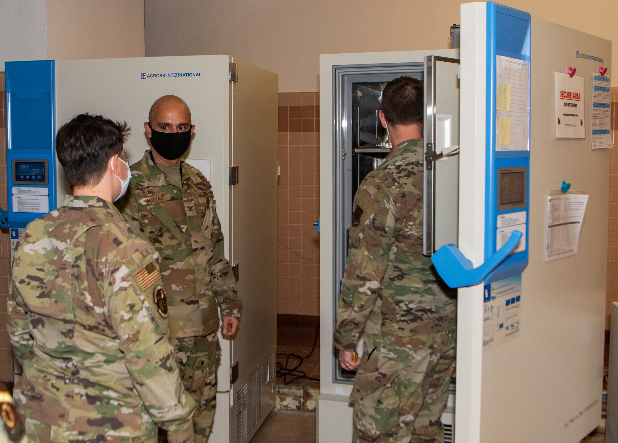 three airmen looking into a freezer