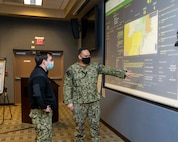 Navy Operations Specialist 1st Class Jose Mendez, conducts a watch turnover with Operations Specialist 2nd Class Dillon Devillier in Task Force North East's Joint Operations Center as part of a 24-hour enhanced watch during distributed operations in support of COVID-19 vaccine operations, Feb. 13, 2021.