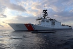 Coast Guard Cutter Munro (WMSL 755) boarding team member sits atop an interdicted low-profile vessel in the Eastern Pacific Ocean after crews seized 3,439 pounds of cocaine from the LPV, Jan. 27, 2021.