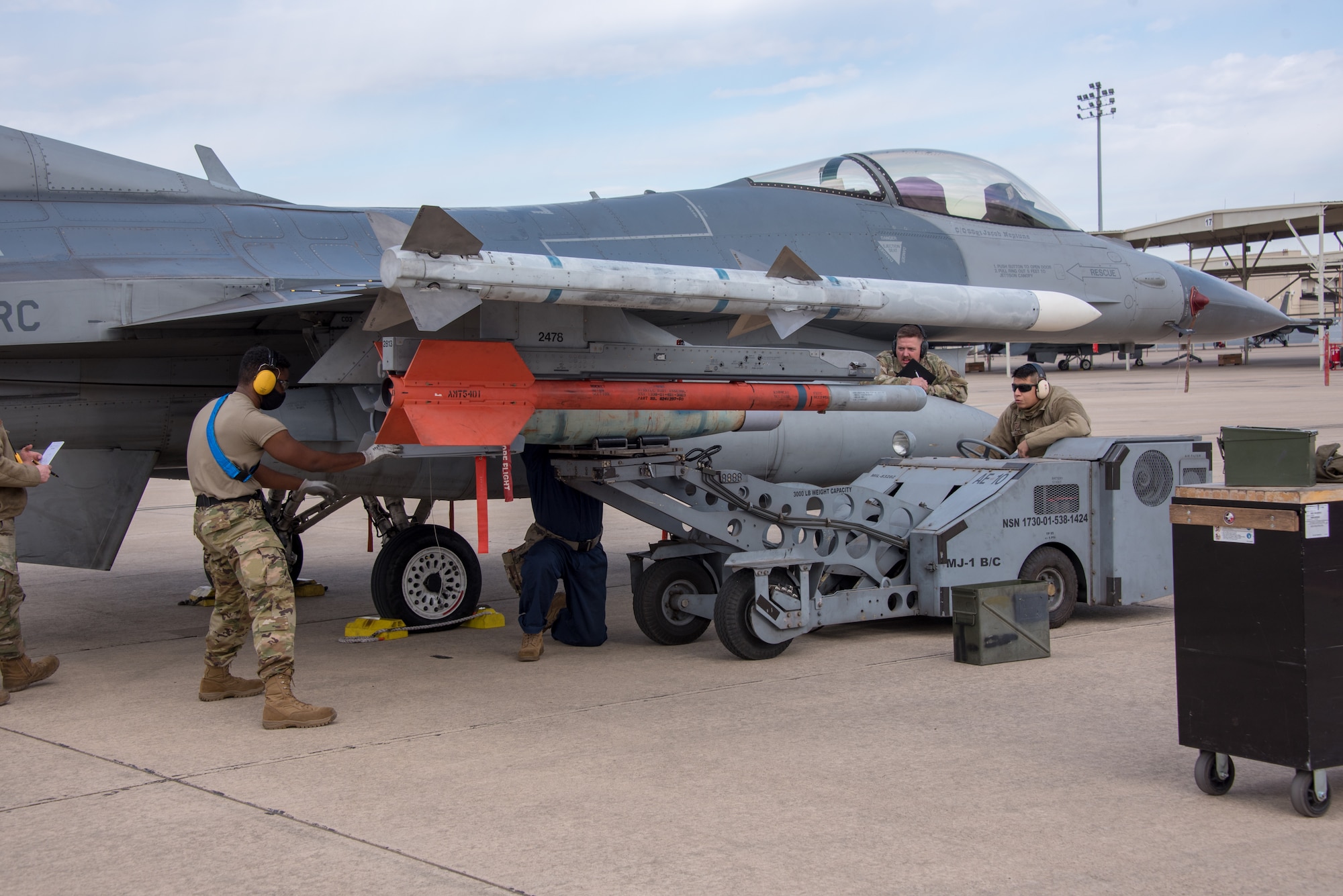 (Left) Tech. Sgt. Shawn Wood, 301st Fighter Wing Aircraft Maintenance Squadron load crew lead, (center) Senior Airman Brandon Knuckles and (right) Senior Airman Emanuel Aguilar load a GBU-12 bomb to the 301st Fighter Wing’s F-16, while being evaluated by (center right) Tech. Sgt. Dakota Daniel during a weapons load competition at U.S. Naval Air Station Joint Reserve Base Fort Worth, Texas on February 5, 2021. The weapons load competition occurs annually, giving the weapons sections a chance to put their four weapons load crews head-to-head loading munitions, testing their knowledge and conducting a uniform inspection to see who the best is. (U.S. Air Force photo by Senior Airman William Downs)