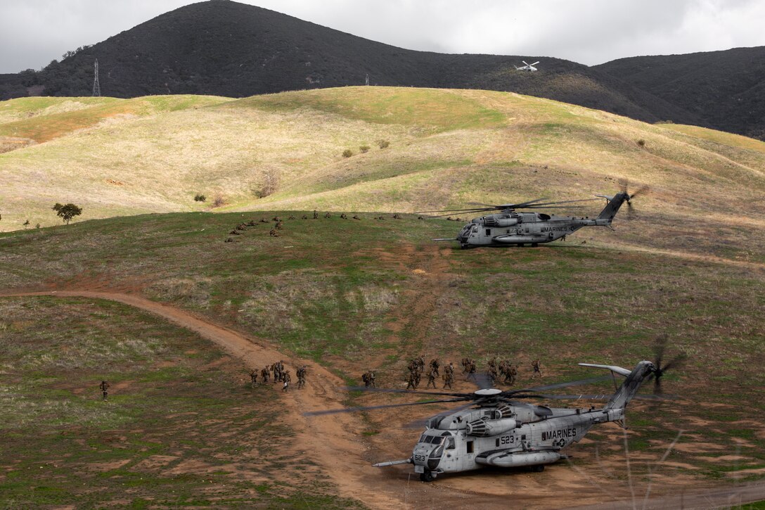 A group of Marines gather next to a large military helicopter.