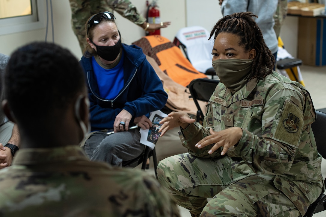 An Airmen talks to another service member and a person in civilian clothes.