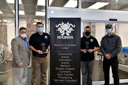 From left to right: Naval Surface Warfare Center, Port Hueneme Division (NSWC PHD)  Deputy Technical Director Vance Brahosky; Ventura Tech Bridge Director and NSWC PHD Office of Research and Technology Applications Manager Alan Jaeger; Camarillo, California-based Matter Labs Director Bryan Went and Fathomwerx Lab Manager Mark Thompson in front of the new 3D printing lab with their Ventura County Economic Development Association award that they accepted virtually Friday, Jan. 15.