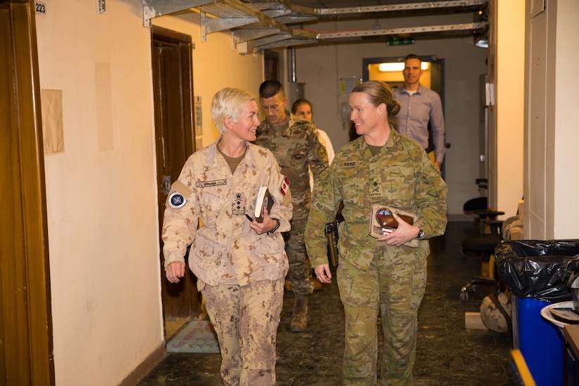 Two general officers walk through a hall.