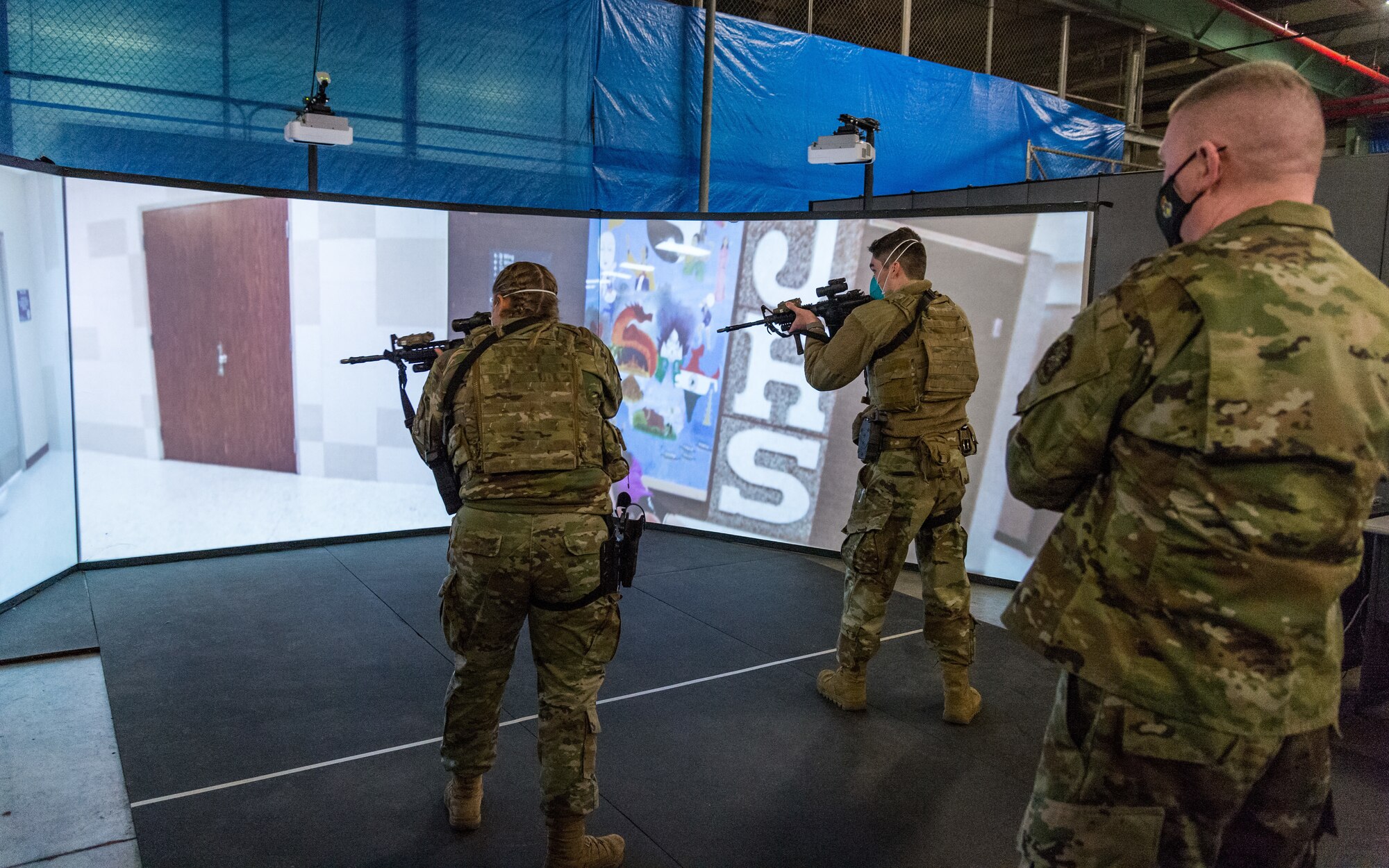 Chief Master Sgt. Chad Bickley, 18th Air Force command chief, observes Airmen 1st Class Kyra Williams and Travis Cross Manhart, both 436th Security Forces Squadron response force members, engaging in an active shooter training exercise using the Multiple Interactive Learning Objectives (MILO) firearm training simulator during a tour of the 436th SFS training facility at Dover Air Force Base, Delaware, Feb.12, 2021. Bickley visited Dover AFB to experience firsthand how Dover Airmen contribute to the 18th Air Force mission of warfighter readiness and sustainment. (U.S. Air Force photo by Roland Balik)