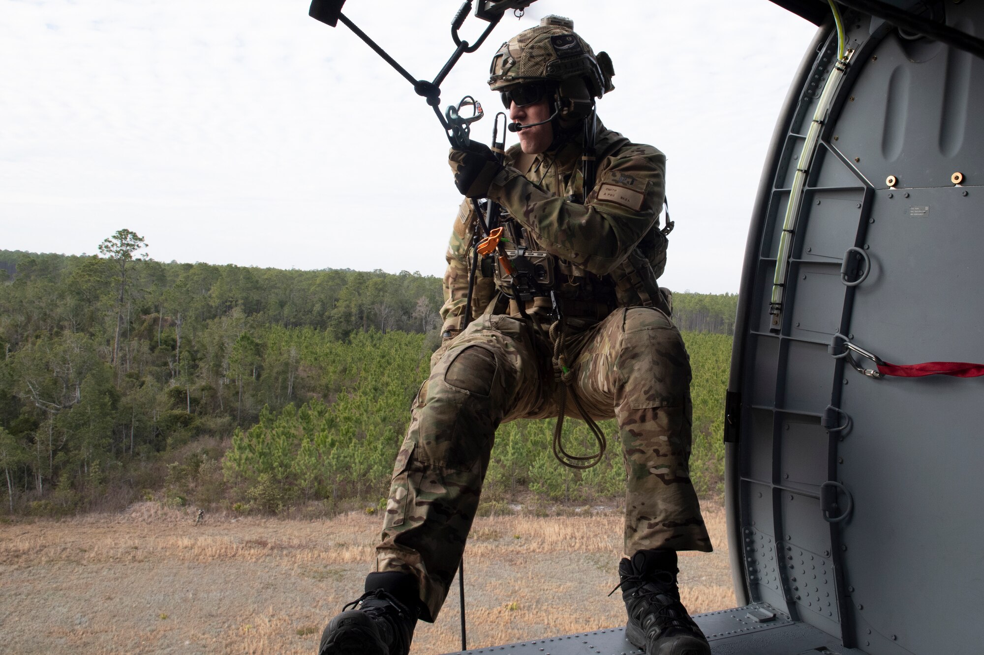 A rescue airman prepares to descend rappel line from a helicopter.