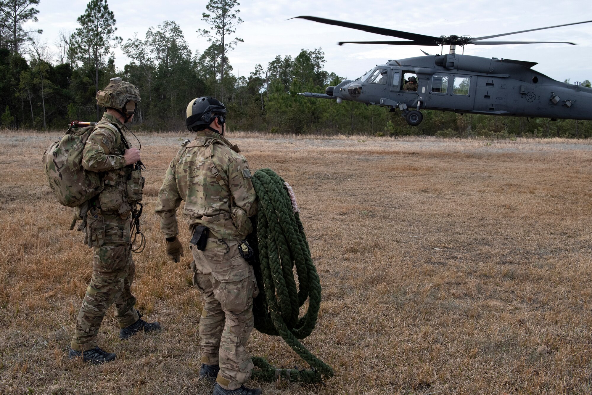 A photo of two rescue airmen waiting for a helicopter to land.