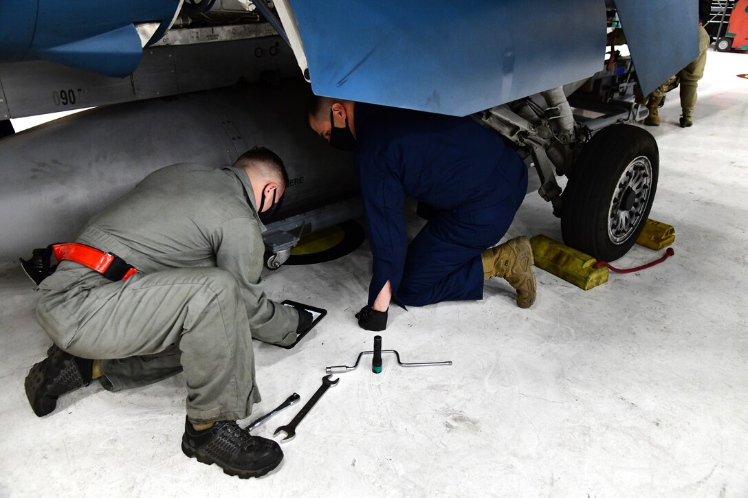 Tech. Sgt. James Whittle, 926th Aircraft Maintenance Squadron, supervises Col. Michael Cabral, 926th Wing Vice commander, as he helps install a 300 gallon center line external fuel tank, Feb. 18, at Nellis Air Force Base, Nevada. Cabral joined the Reserve maintainers as they demonstrated how they utilize Technical Orders to maintain Nellis AFB aircraft.