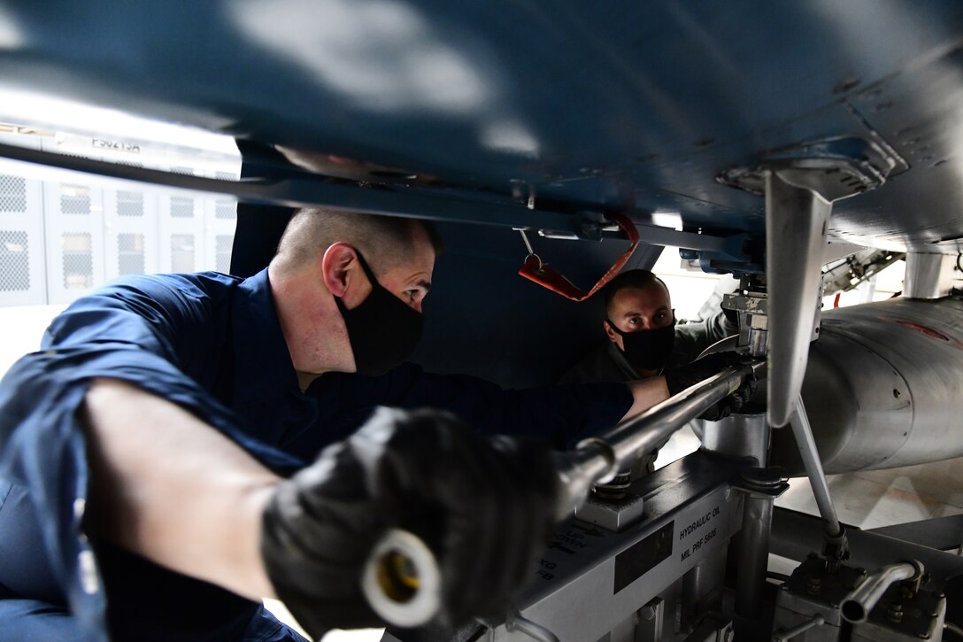 Tech. Sgt. James Whittle, 926th Aircraft Maintenance Squadron, supervises Col. Michael Cabral, 926th Wing Vice commander, as he helps install a 300 gallon center line external fuel tank, Feb. 18, at Nellis Air Force Base, Nevada. Cabral joined the Reserve maintainers as they demonstrated how they utilize Technical Orders to maintain Nellis AFB aircraft.