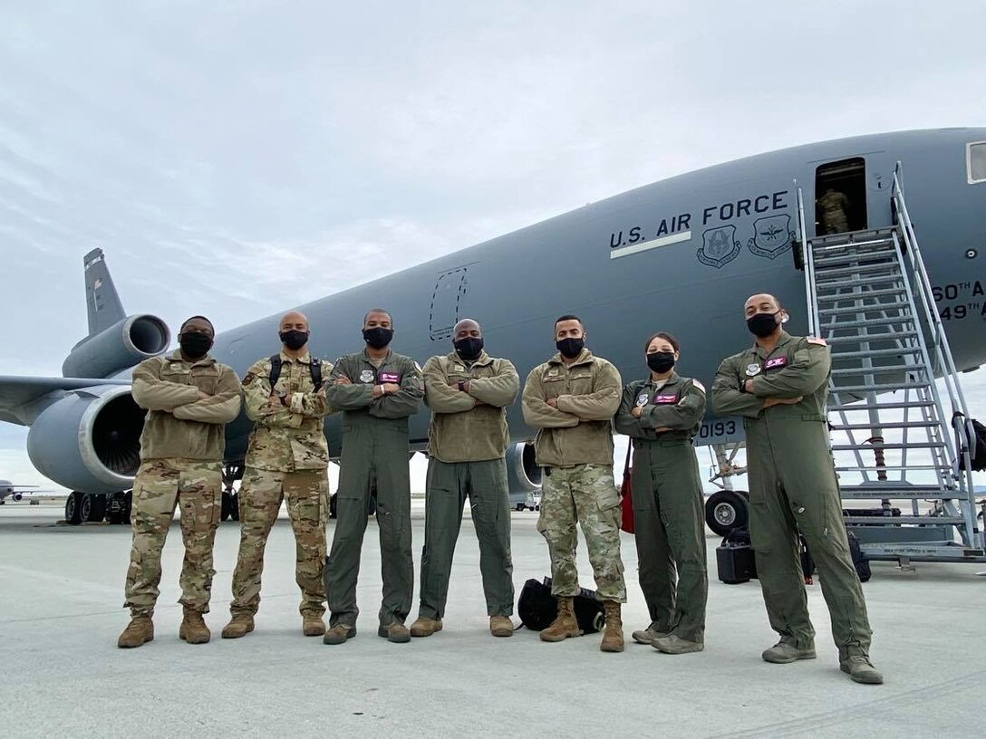 Airmen in flight suits stand in front of a KC-10 Extender aircraft.