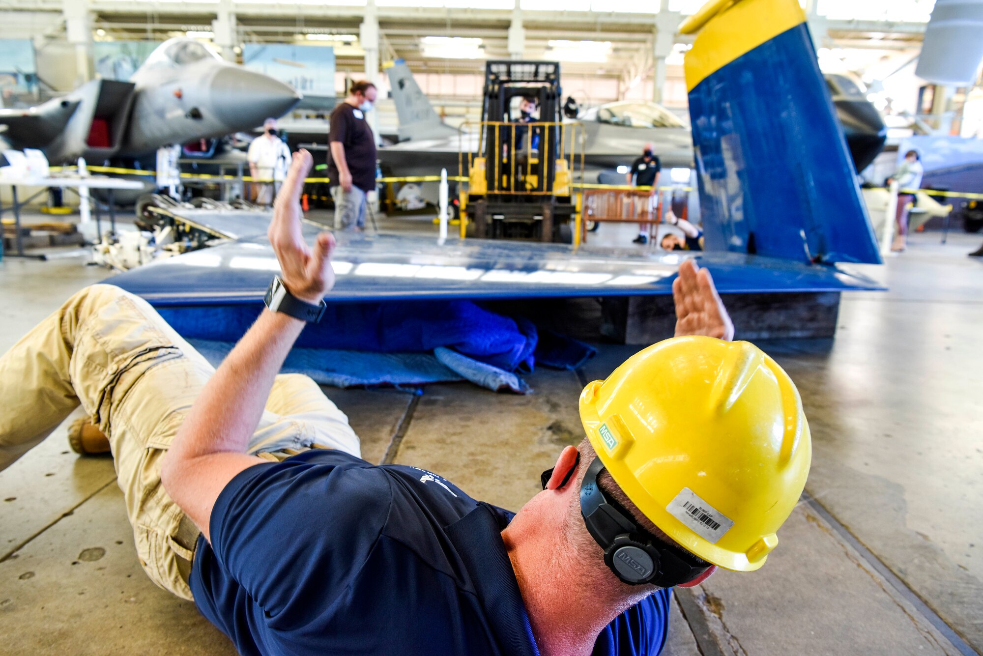 U.S. Air Force Master Sgt. Brandon Baimbridge, 735th Air Mobility Squadron superintendent, directs a forklift carrying the wing of a U.S. Navy Blue Angel F/A-18 on Joint Base Pearl Harbor-Hickam, Hawaii, Feb. 9, 2021.  The Pearl Harbor Aviation Museum’s mission is to steward America’s first aviation battlefield of World War II – sharing the artifacts, personal stories, the impact and response to the attack on December 7, 1941, and the Pacific region battles that followed. (U.S. Air Force photo by Tech. Sgt. Anthony Nelson Jr.)