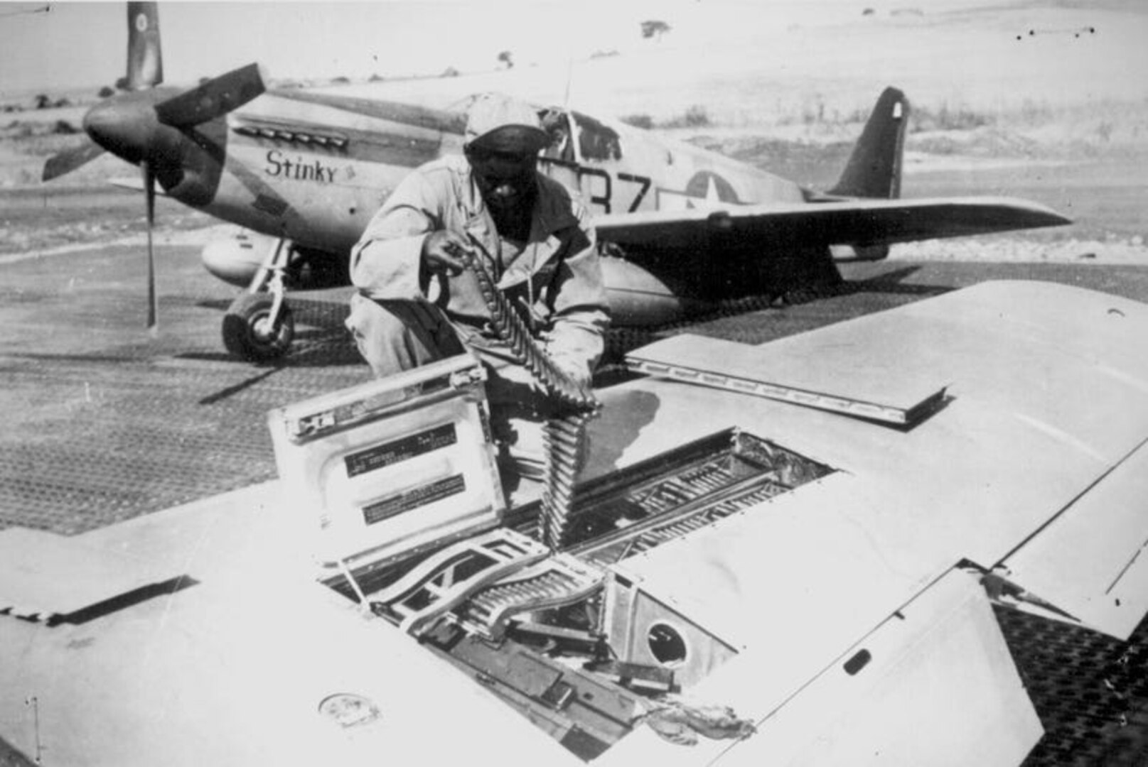 Editor’s note: photo and caption were pulled from the National Archives Catalog.
An armorer of the 15th U.S. Air Force checks ammunition belts of the .50 caliber machine guns in the wings of a P-51 Mustang fighter plane before leaving an Italian base for a mission against German military targets. The 15th Air Force was organized for long-range assault missions, and its fighters and bombers range over enemy targets in occupied and satellite nations, as well as Germany itself. 
Ca. September 1944. 208-MO-18H-32984.