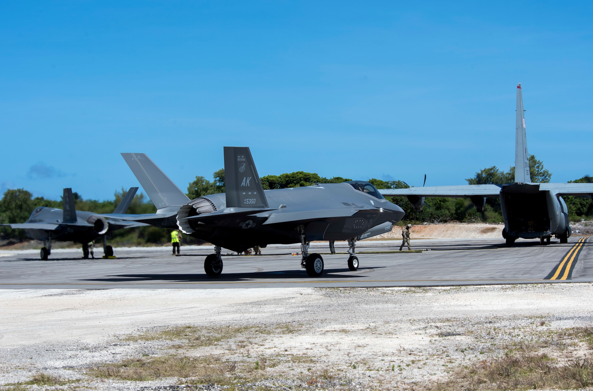 Two F-35A Lightning II assigned to Eielson Air Force Base, Alaska, await to refuel from a C-130J Super Hercules assigned to the 36th Airlift Squadron at Yokota Air Base, Japan, at Northwest Field as part of Agile Combat Employment (ACE) multi-capable Airmen training during Cope North 21 at Andersen AFB, Guam, Feb. 16, 2021.