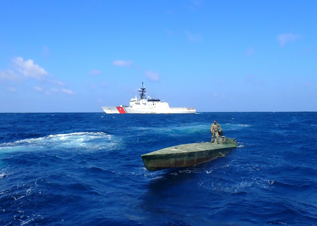 A Coast Guard Cutter Bertholf (WMSL 750) boarding team member stands atop an interdicted low-profile vessel in the Eastern Pacific Ocean, Feb. 1, 2021.