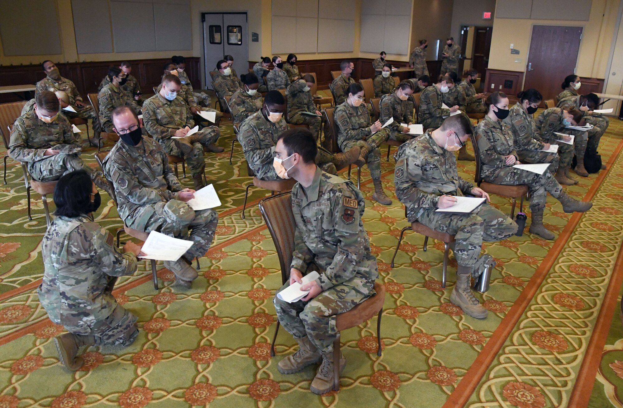 Members of the 81st Medical Group completes inprocessing paper work for deploying inside the Bay Breeze Event Center at Keesler Air Force Base, Mississippi, Feb. 16, 2021. More than 150 Dragon Medics were preparing to deploy to support our nation's COVID-19 vaccine inoculations requirements. (U.S. Air Force photo by Kemberly Groue)