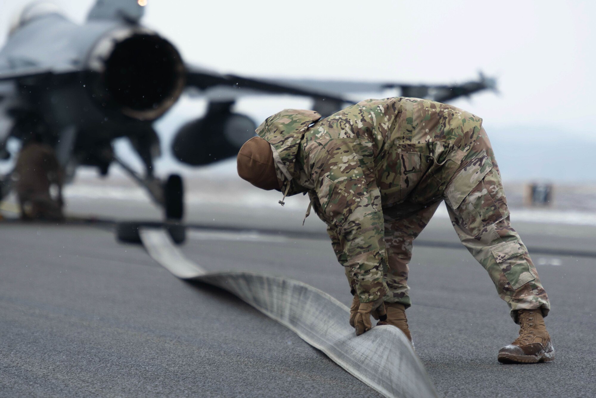 An Airman inspecting a barrier arresting kit during training.