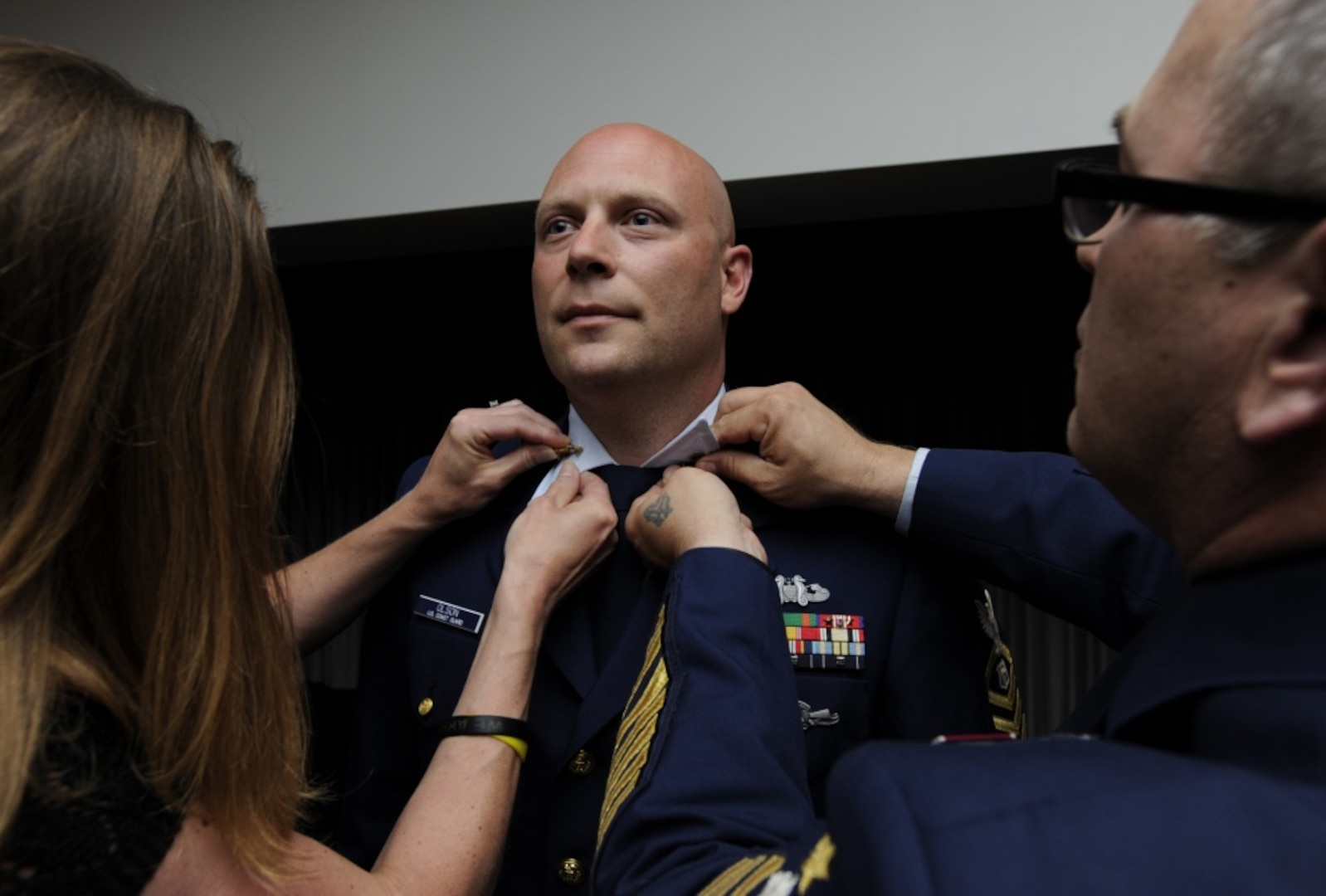 Cyndy Olson and Master Chief Petty Officer of the Coast Guard Steven Cantrell affix new collar devices to Ryan Olson's uniform during the 2014 Coast Guard Enlisted Persons of the Year Banquet at Joint Base Anacostia-Bolling in Washington, D.C., May 7, 2015. During the ceremony, Olson was recognized as the Enlisted Person of the Year - Reserve Component, an honor that comes with a meritorious advancement - in Olson's case, an advancement from petty officer first class to chief petty officer. (U.S. Coast Guard photo by Chief Petty Officer Kyle Niemi)