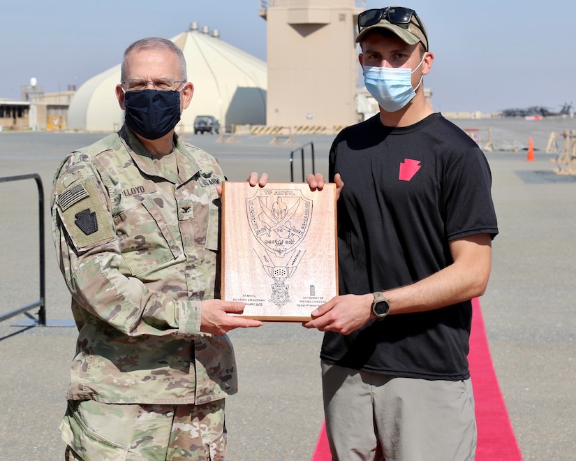 U.S. Army Capt. Matthew Groff, right, a UH-60 pilot with 2-104th General Support Aviation Battalion, 28th Expeditionary Combat Aviation Brigade, receives a handmade plaque from Col. Howard Lloyd, 28th ECAB commander, for being the top finisher in the Task Force Anvil Half-Marathon. About 120 Soldiers raced in memory of Michael J. Novosel, Sr., a native of Etna, Pennsylvania, who served for over 40 years as an Army aviator and received the Medal of Honor for rescuing 29 Soldiers during the Vietnam War.